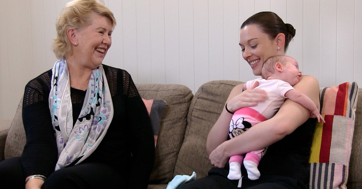 Dr Robyn Thompson smiling with a mother holding her newborn